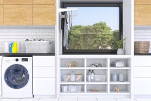 White front-load washer and dryer in organised laundry room. Laundry basket and cleaning supplies on shelves with a window above to ensure proper ventilation in the room. A clothesline hangs on the side.