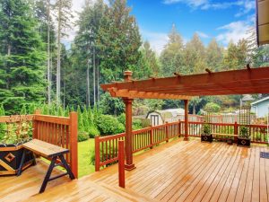 Spacious wooden deck with pergola in a backyard surrounded by trees, illustrating deck permit requirements for elevated structures.