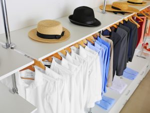 Shop fitting design ideas with neatly arranged shirts, jackets, and hats on sleek, modern racks for a minimalist retail display.